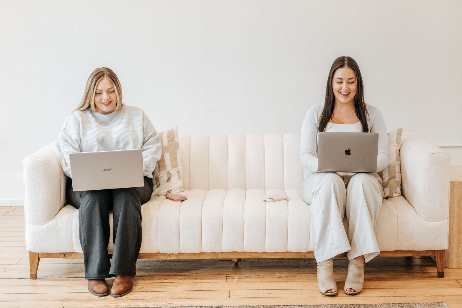 Chanel and Adrianna working on laptops on a sofa